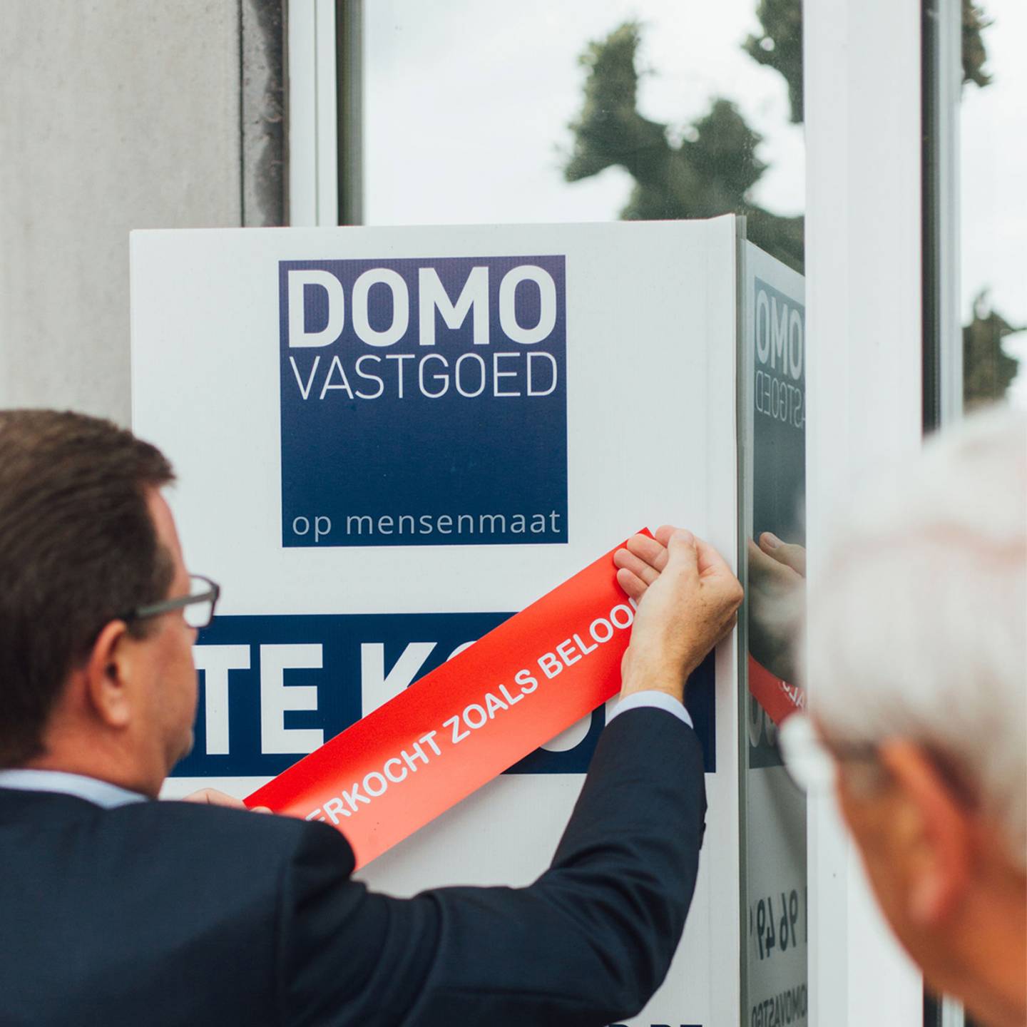 Foto van een man die een sticker aanbrengt op een reclampaneel van DOMO